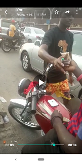 Agbero collects money from a motorcyclist marking the motorcycle after collecting N100 note
